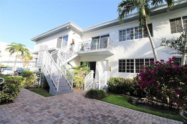 back of property featuring stairway and stucco siding
