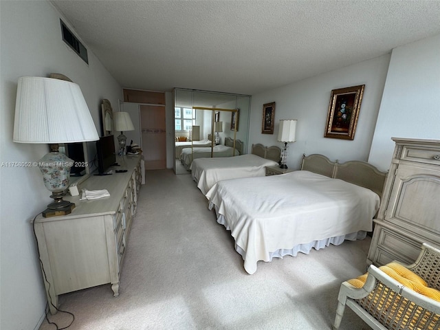 bedroom with visible vents, a textured ceiling, and light carpet
