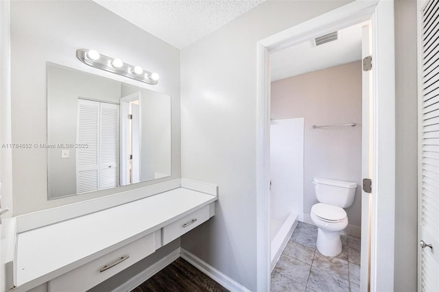 bathroom featuring vanity, toilet, a textured ceiling, baseboards, and visible vents