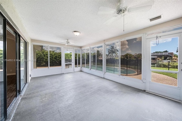 unfurnished sunroom featuring a ceiling fan, visible vents, and a wealth of natural light