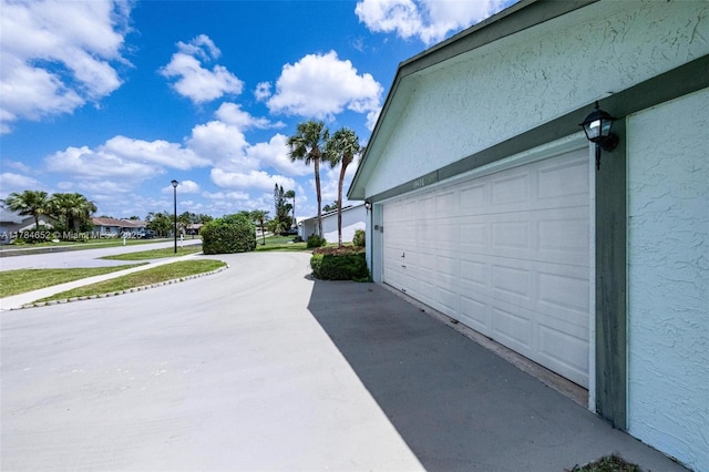 view of side of home featuring a garage, stucco siding, and concrete driveway