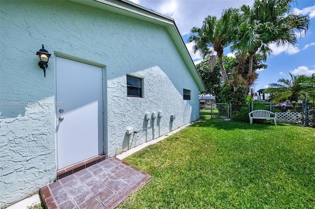 view of property exterior with fence, stucco siding, and a yard