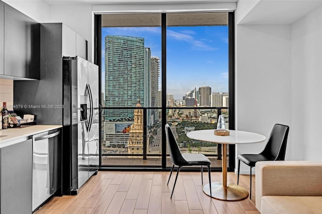 kitchen with a wall of windows, modern cabinets, light wood-type flooring, a city view, and stainless steel appliances