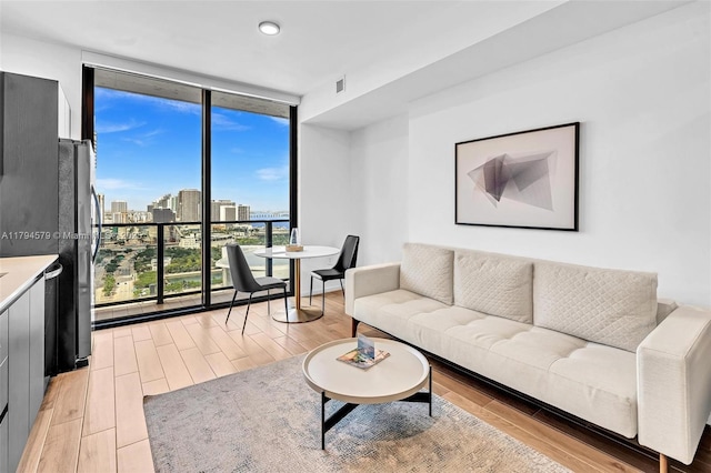 living area featuring a city view, a wall of windows, light wood-style flooring, and visible vents