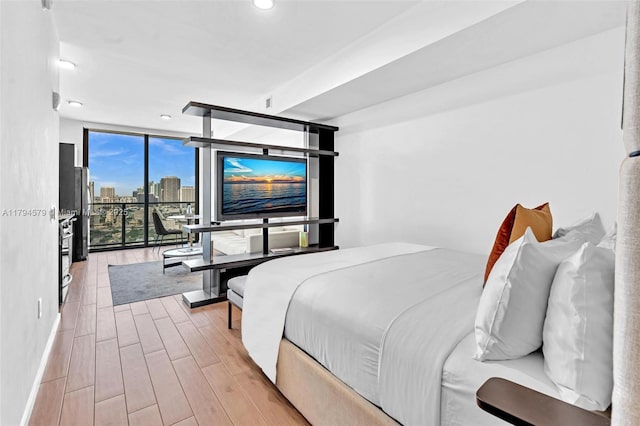 bedroom with recessed lighting, expansive windows, and wood finished floors