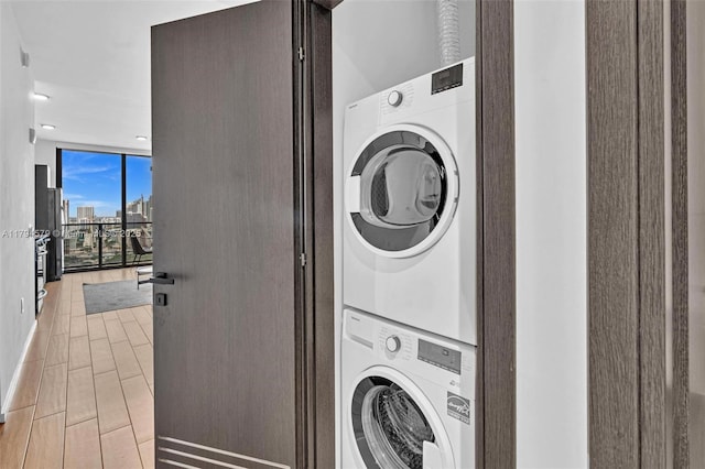 washroom with laundry area, stacked washer and dryer, recessed lighting, a city view, and light wood finished floors