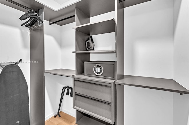 walk in closet with light wood-style floors