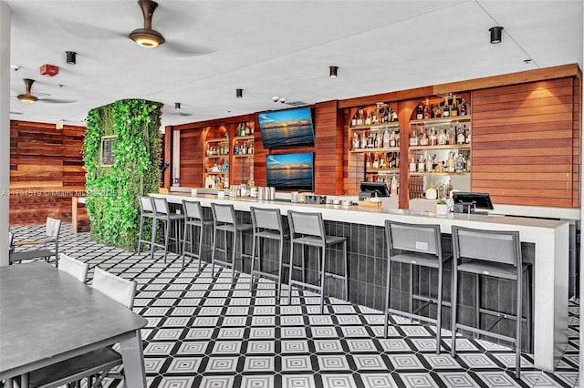 bar featuring ceiling fan, indoor wet bar, and wood walls