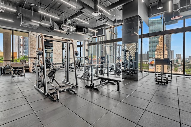 exercise room featuring a wall of windows, a city view, and a towering ceiling