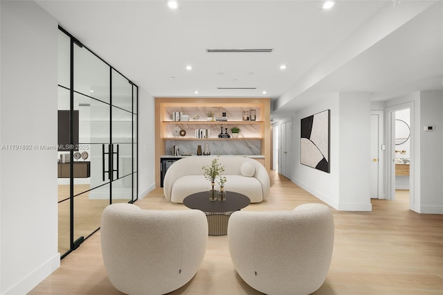 sitting room with baseboards, bar area, and light wood-style floors