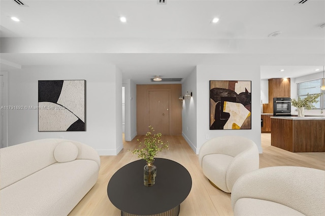 living area with recessed lighting, baseboards, and light wood-type flooring