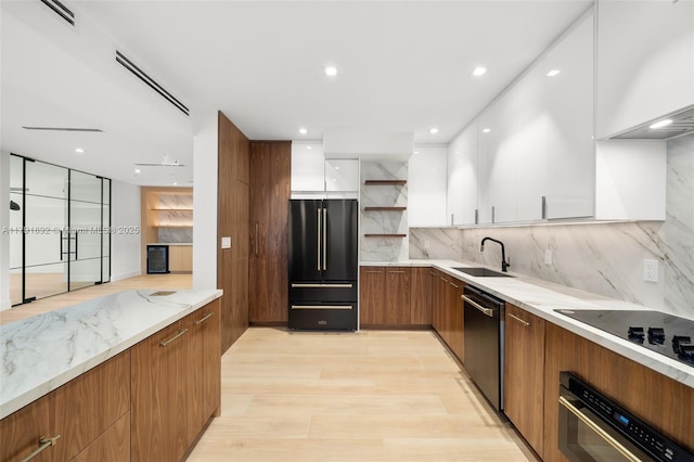 kitchen featuring decorative backsplash, modern cabinets, a sink, black appliances, and white cabinetry