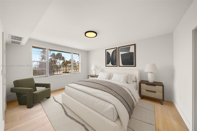 bedroom with baseboards, light wood-style flooring, and visible vents