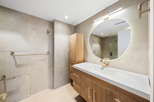 bathroom featuring vanity, a tile shower, and tile walls