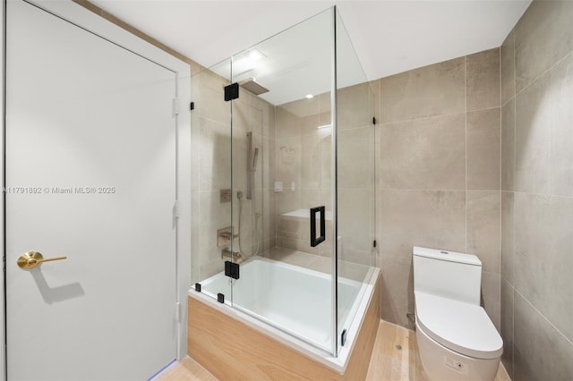 full bathroom featuring tile walls, combined bath / shower with glass door, and toilet