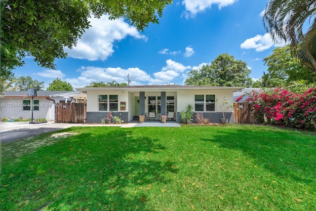 ranch-style home featuring stucco siding, fence, a gate, and a front lawn