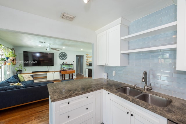 kitchen featuring visible vents, a peninsula, open floor plan, tasteful backsplash, and a sink