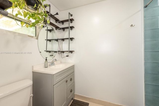 bathroom featuring toilet, baseboards, and vanity