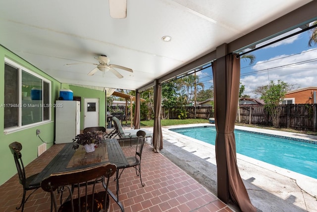 view of swimming pool with ceiling fan, a fenced in pool, a fenced backyard, a patio, and outdoor dining space