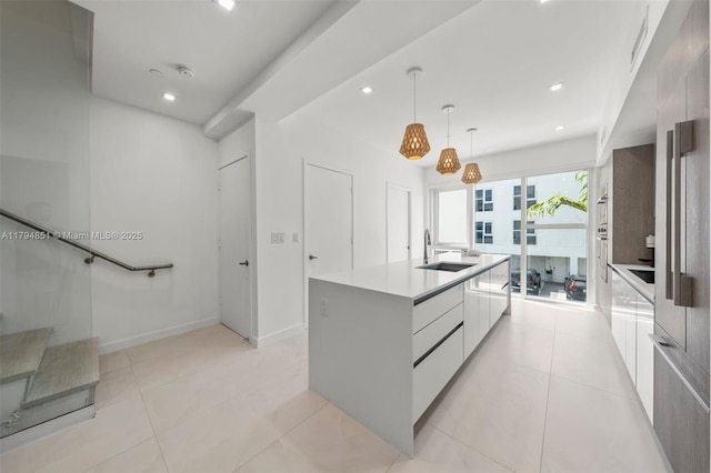 kitchen featuring pendant lighting, modern cabinets, a sink, white cabinetry, and an island with sink