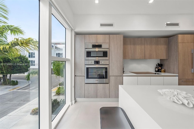 kitchen with light countertops, modern cabinets, stainless steel double oven, and visible vents