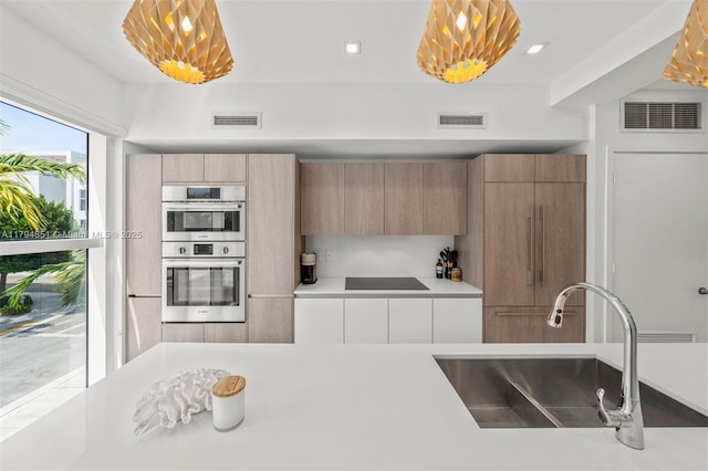 kitchen with black electric cooktop, visible vents, and a sink