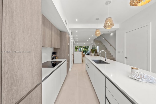 kitchen with a sink, black electric cooktop, modern cabinets, and light countertops