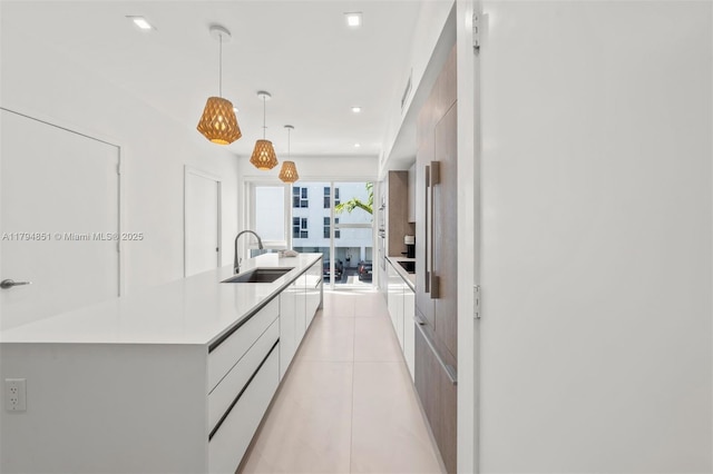 kitchen with modern cabinets, a spacious island, a sink, light countertops, and white cabinetry