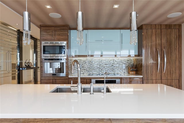 5875 Collins Ave Unit 1908, Miami Beach, FL 33140 - kitchen with brown cabinetry, modern cabinets, tasteful backsplash, a sink, and appliances with stainless steel finishes