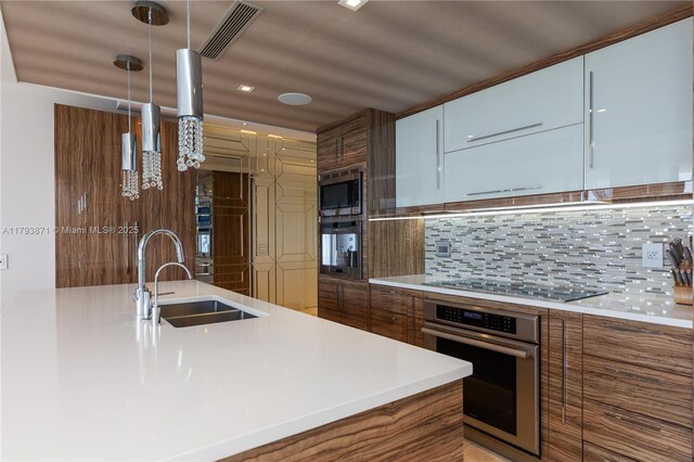 5875 Collins Ave Unit 1908, Miami Beach, FL 33140 - kitchen with visible vents, decorative backsplash, modern cabinets, a sink, and appliances with stainless steel finishes