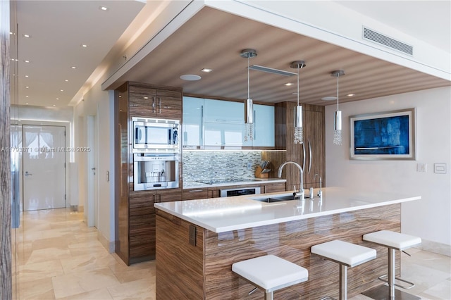 5875 Collins Ave Unit 1908, Miami Beach, FL 33140 - kitchen with visible vents, modern cabinets, a kitchen bar, a sink, and appliances with stainless steel finishes