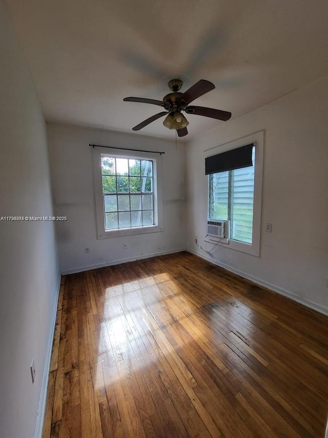 empty room featuring wood-type flooring, a ceiling fan, baseboards, and cooling unit