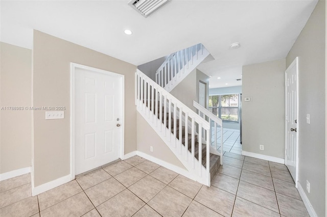 interior space featuring baseboards, visible vents, light tile patterned floors, and stairway