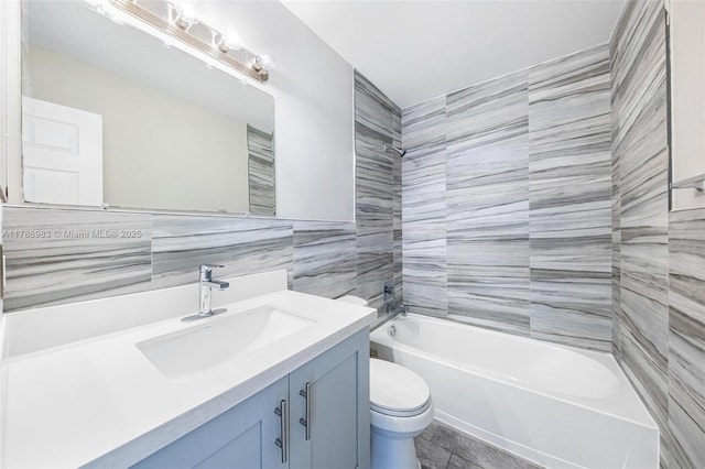 bathroom with toilet, tile walls, shower / washtub combination, and vanity
