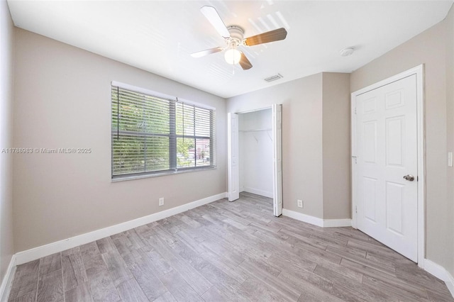 unfurnished bedroom featuring a ceiling fan, visible vents, baseboards, a closet, and light wood-style floors