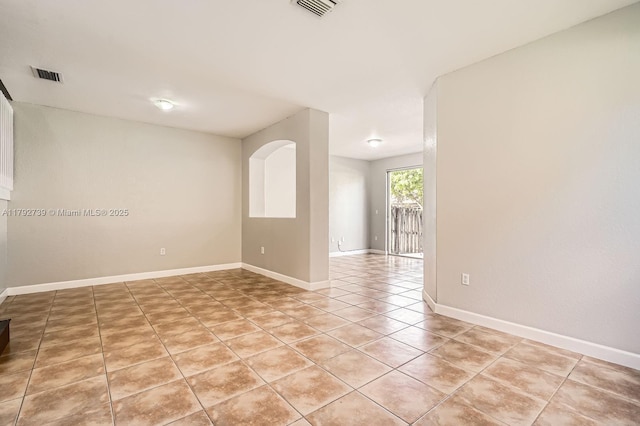 empty room featuring baseboards, visible vents, and light tile patterned floors