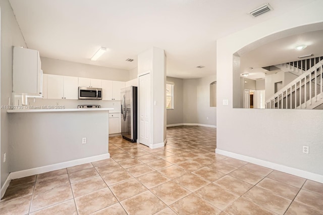 kitchen featuring visible vents, appliances with stainless steel finishes, light tile patterned floors, light countertops, and white cabinetry