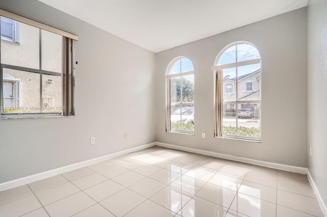 empty room with baseboards and tile patterned floors