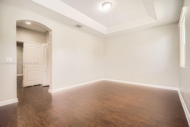 unfurnished room featuring arched walkways, visible vents, and dark wood finished floors