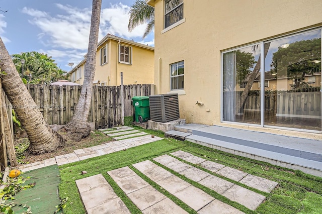 rear view of house featuring a patio, fence, central AC unit, and stucco siding