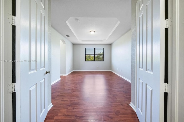 8904 SW 229th St, Cutler Bay, FL 33190 - empty room with visible vents, baseboards, a raised ceiling, arched walkways, and dark wood finished floors