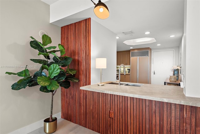 kitchen with a sink, a peninsula, recessed lighting, paneled built in refrigerator, and visible vents