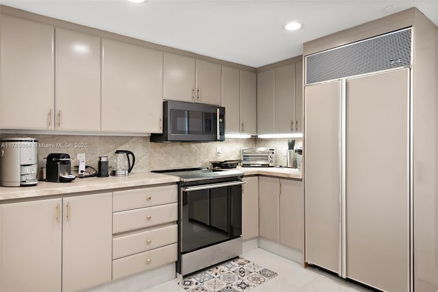 kitchen with stainless steel electric range, paneled built in fridge, black microwave, light countertops, and a toaster