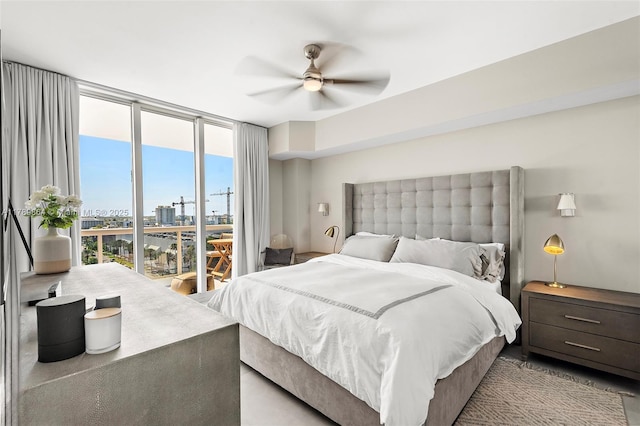 bedroom with expansive windows, a ceiling fan, and a city view