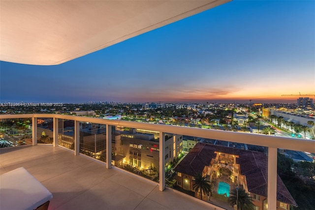 balcony at dusk featuring a view of city