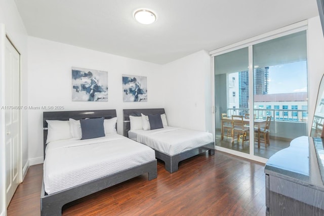 bedroom with a wall of windows, wood finished floors, and access to exterior