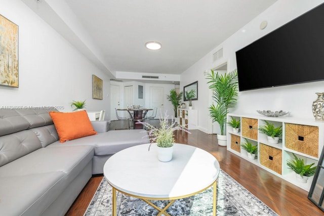 living area featuring visible vents, baseboards, and wood finished floors
