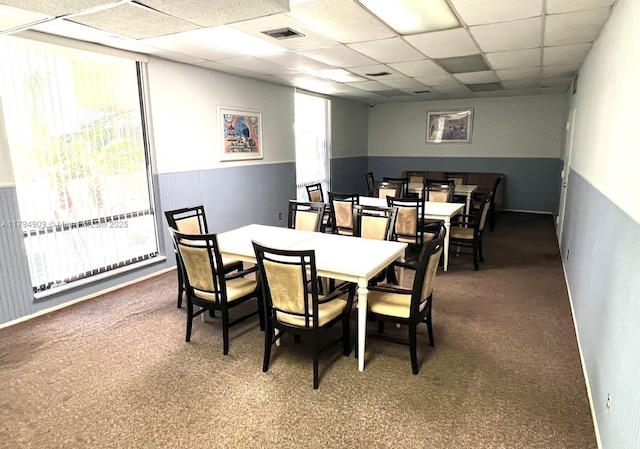 carpeted dining space with visible vents and a paneled ceiling
