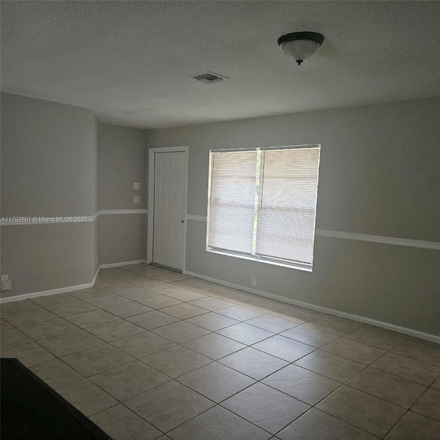 spare room featuring baseboards, visible vents, and tile patterned flooring