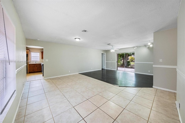 spare room featuring a wealth of natural light, a ceiling fan, light tile patterned flooring, and visible vents